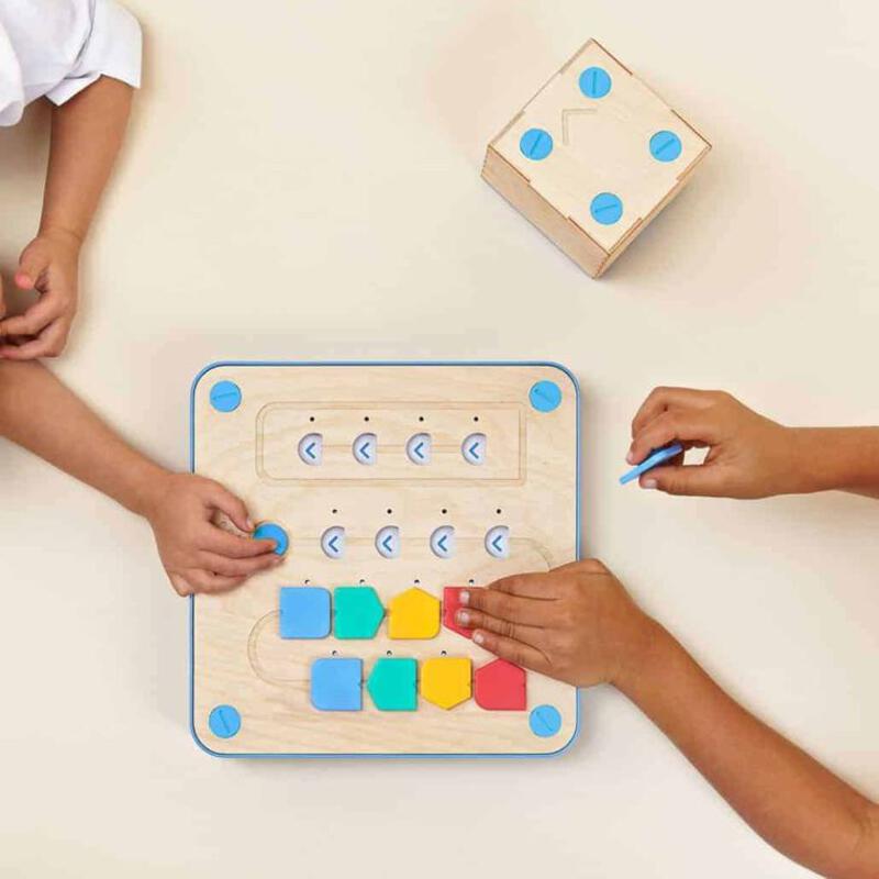 This may contain: two children playing with wooden blocks on the floor and one child is using a pen to write