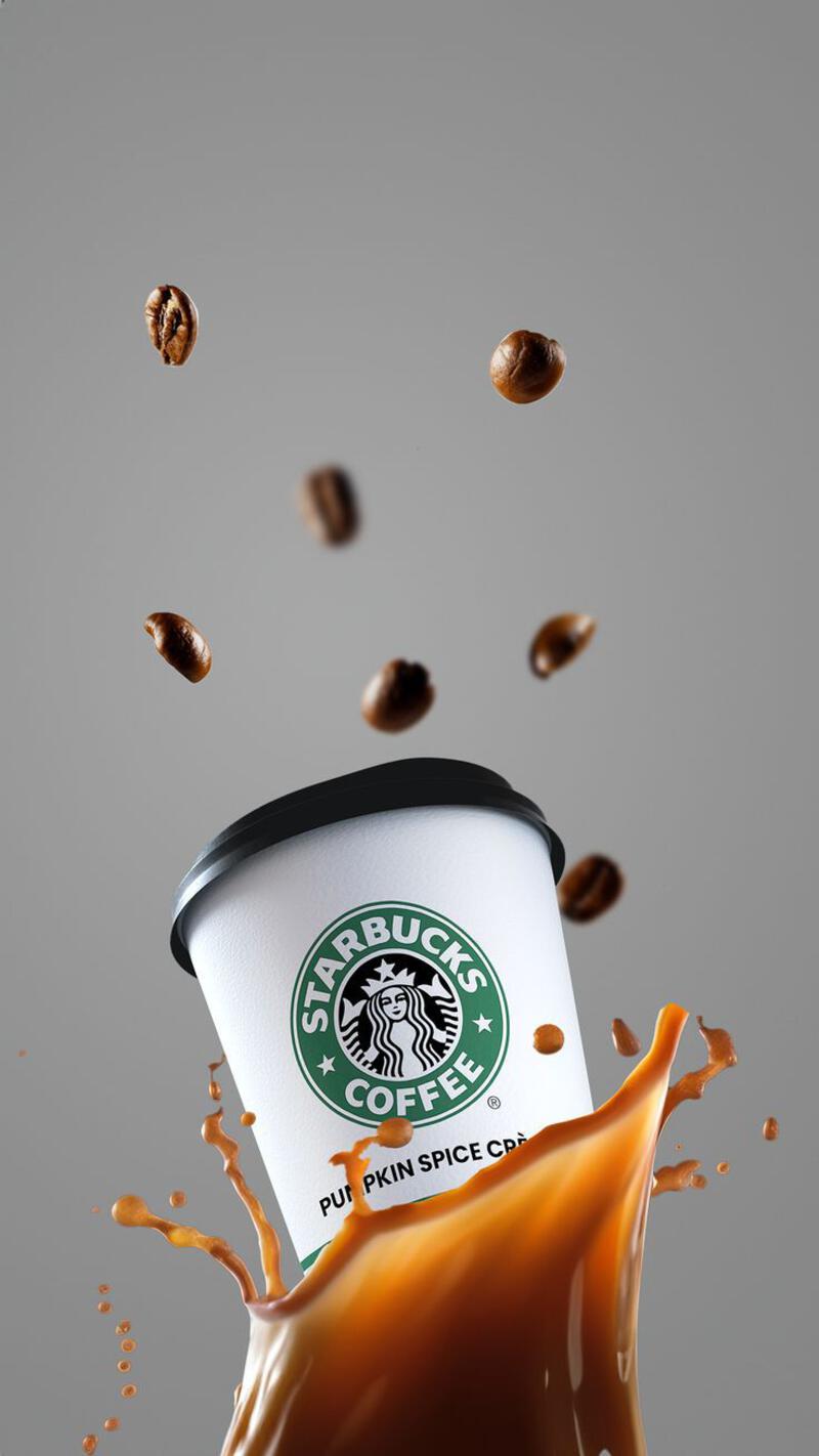 This may contain: a cup of starbucks coffee is being poured into the ground with some coffee beans coming out of it