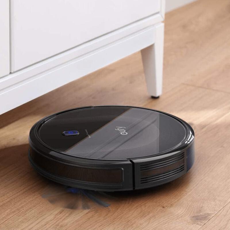 This may contain: a black robot vacuum on the floor in front of a dresser