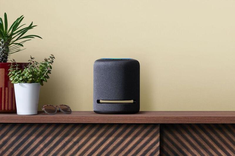 This may contain: a black speaker sitting on top of a wooden table next to a potted plant