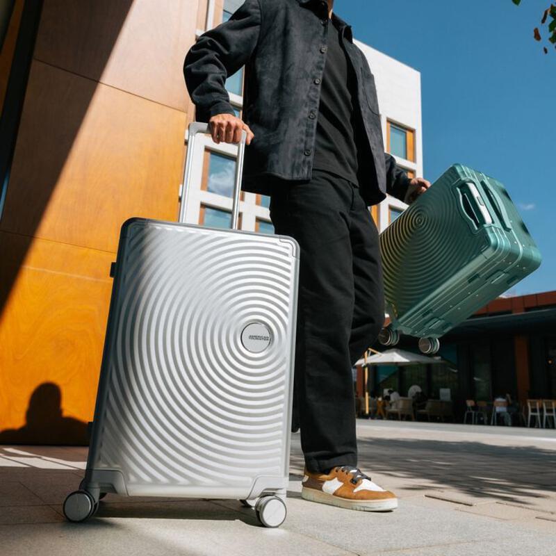 This may contain: a man holding two pieces of luggage on wheels
