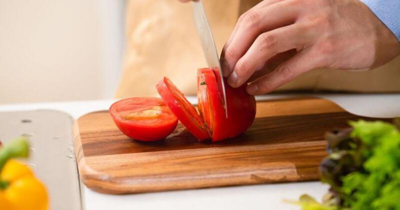This may contain: a person cutting tomatoes on top of a wooden cutting board