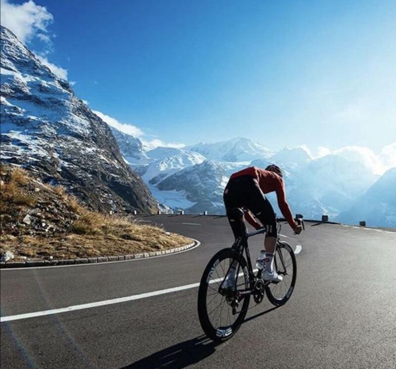 This may contain: a man riding a bike down a winding road