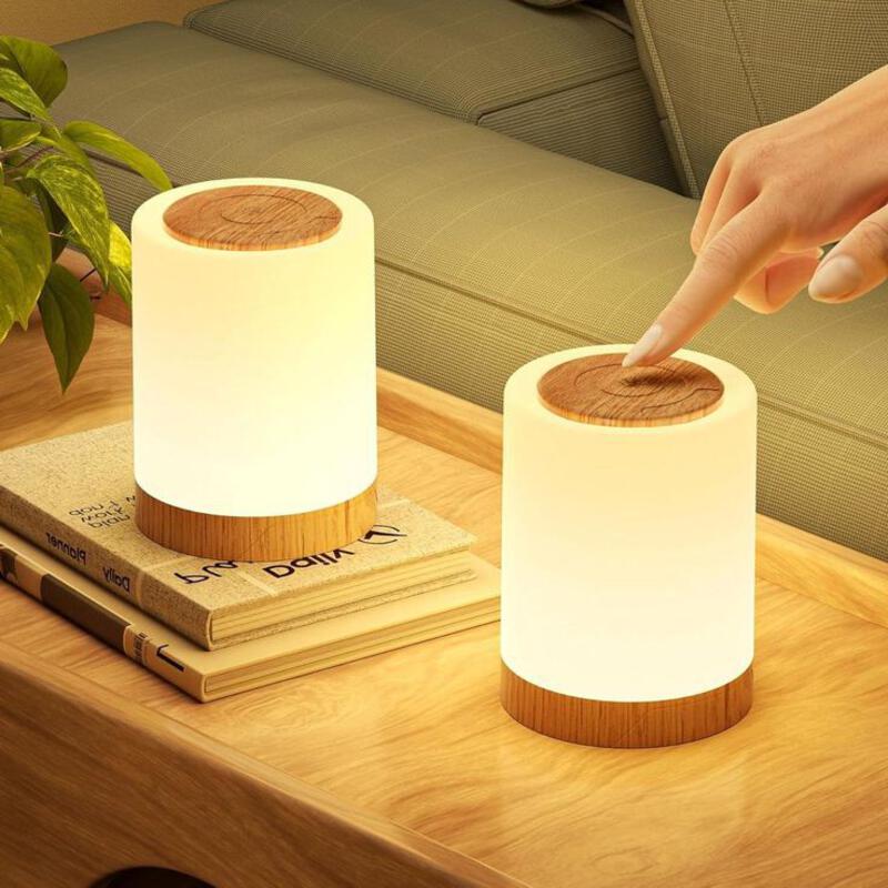 This may contain: a person touching the top of two lamps on a wooden table next to a couch