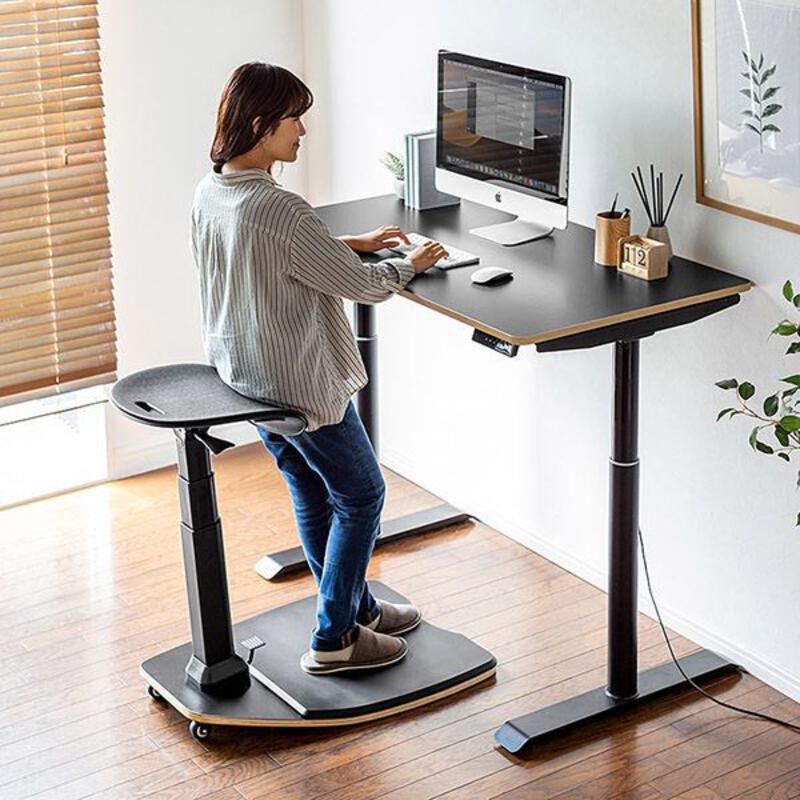 This may contain: a woman standing at a computer desk with a monitor and keyboard on top of it