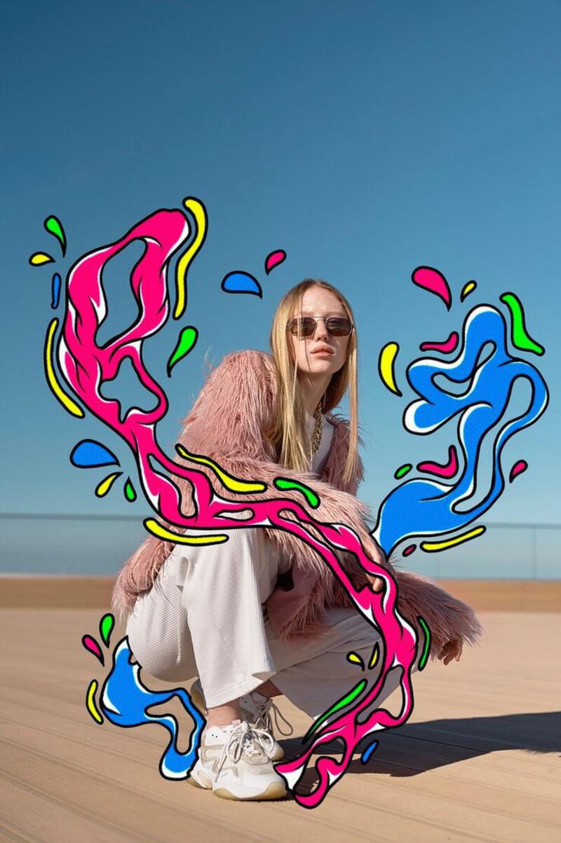 This may contain: a woman sitting on top of a wooden floor next to a skateboard covered in graffiti