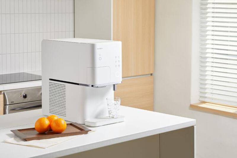 This may contain: a white machine sitting on top of a counter next to oranges and a knife