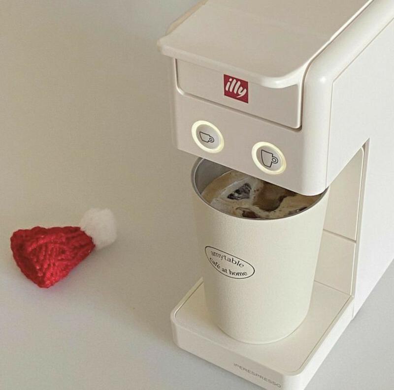 This may contain: a white coffee maker with a red heart on the table next to it and a cup holder