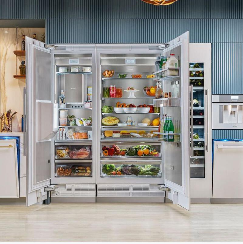 This may contain: an open refrigerator with its doors wide open in a kitchen area that has blue walls and wood flooring