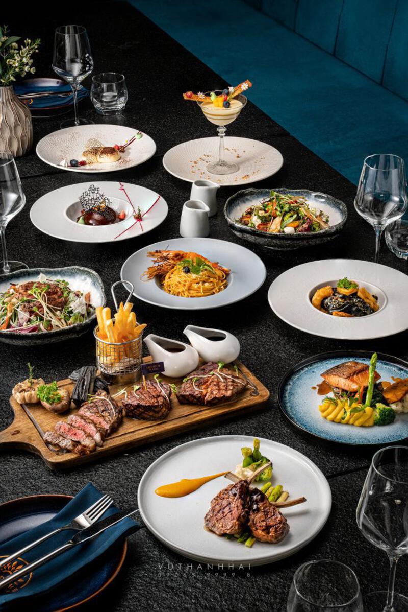 This may contain: a table topped with lots of plates and bowls filled with different types of food next to wine glasses