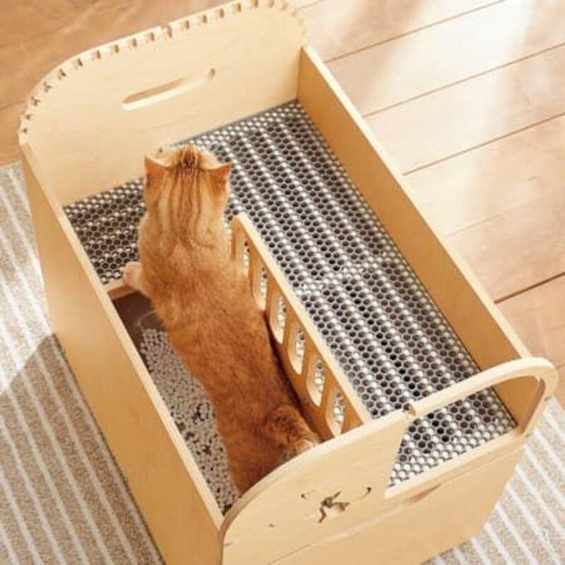 This may contain: an orange cat sitting in a wooden crate on top of a rug and looking up at the floor