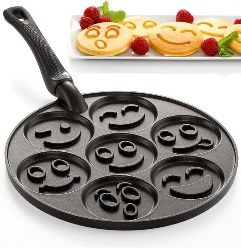 This may contain: a pan with smiley faces on it next to some raspberries and pancakes in the background