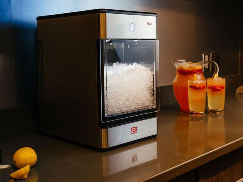 This may contain: an ice machine sitting on top of a counter next to two glasses filled with liquid
