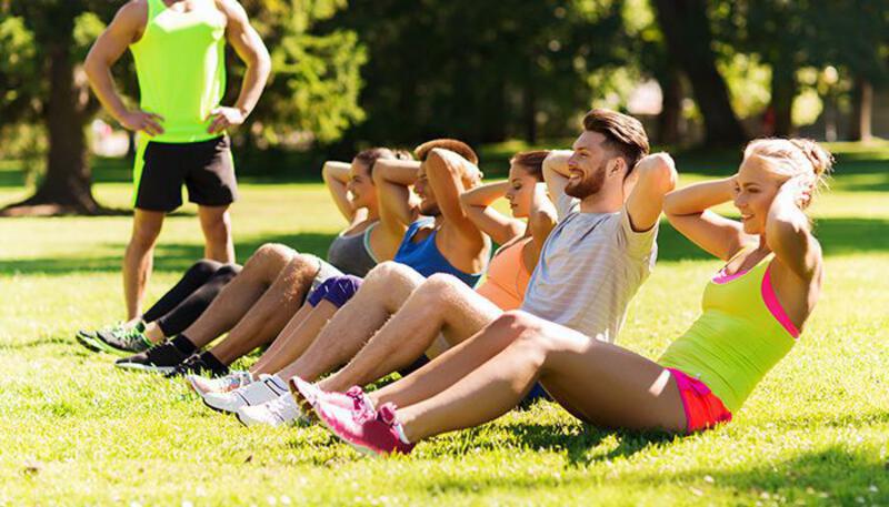 This may contain: a group of people sitting on the grass doing exercises