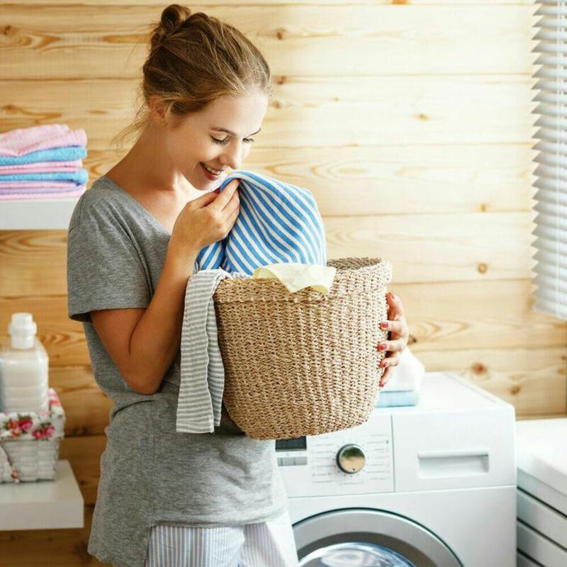 This may contain: a woman holding a laundry basket next to a washing machine