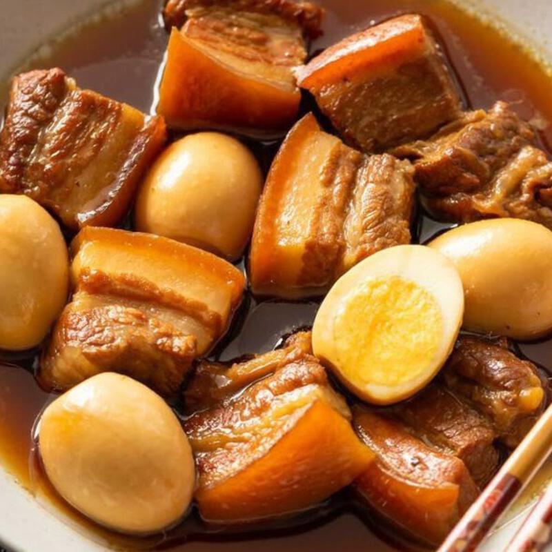 This may contain: a white bowl filled with beef and potatoes next to chopsticks on a table
