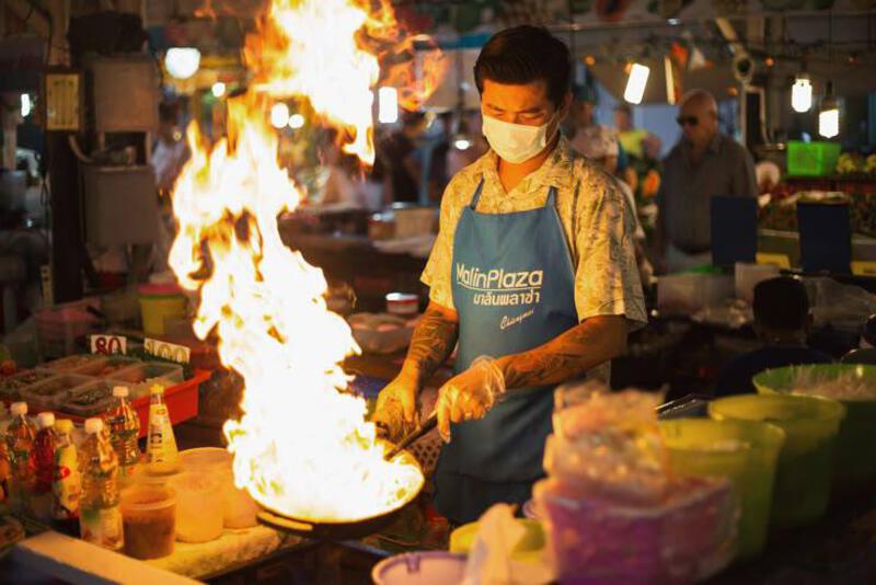 This may contain: a man wearing a face mask cooking on a grill with flames in the air behind him
