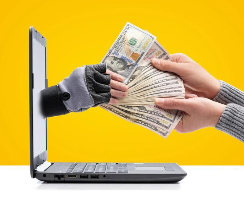This may contain: a person is holding cash in front of a laptop computer with gloves on their hands
