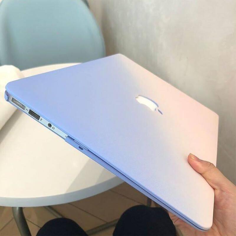 This may contain: a person holding up a laptop computer on top of a white table in front of a blue chair