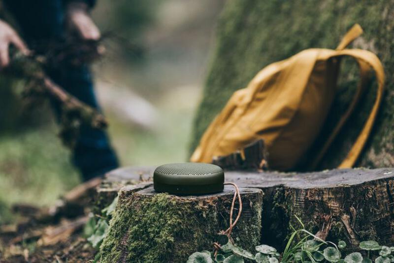 This may contain: a green speaker sitting on top of a tree stump in the middle of a forest