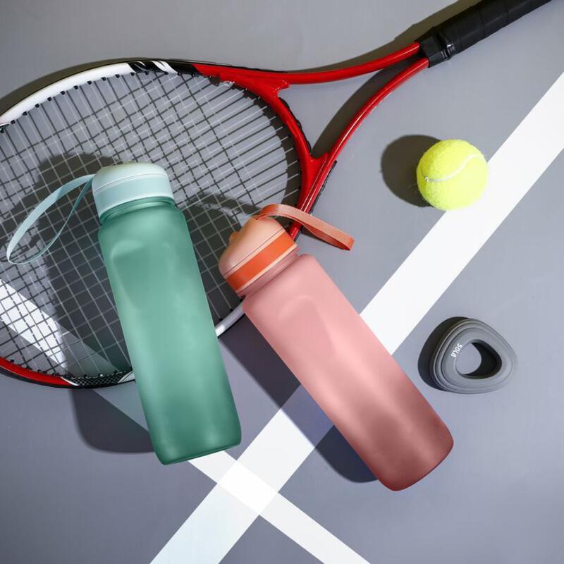 This may contain: a tennis racket and two bottles on a court