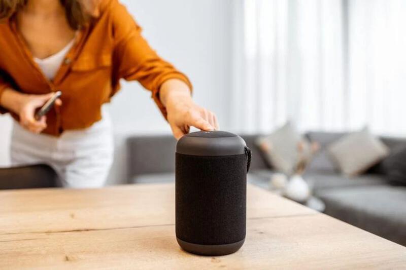 This may contain: a woman opening up a black speaker on top of a wooden table