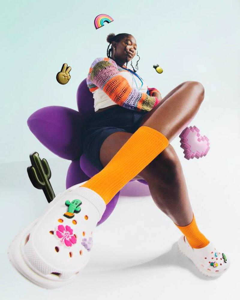 This may contain: a woman sitting on top of a purple chair next to cactuses and other objects