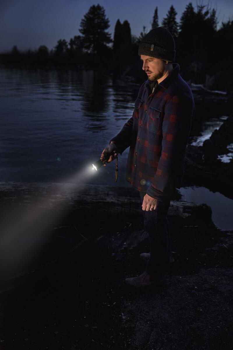 This may contain: a man is standing by the water holding a flashlight