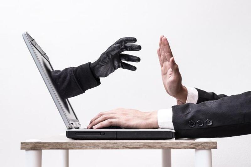 This may contain: two hands reaching out towards each other over a laptop computer on a wooden table in front of a white wall