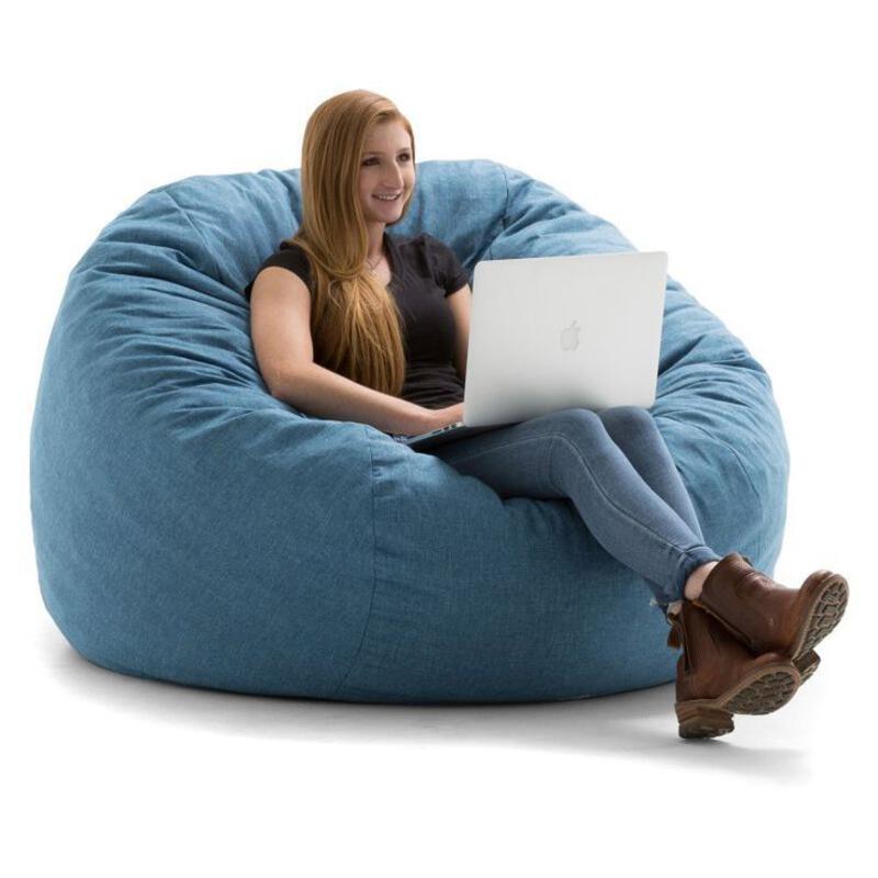 This may contain: a woman sitting on a bean bag chair using a laptop