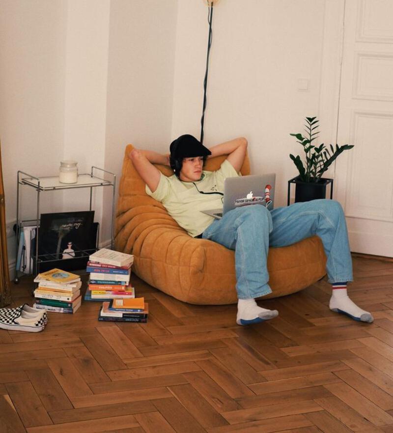 This may contain: a man sitting in a bean bag chair with his laptop on the floor next to him