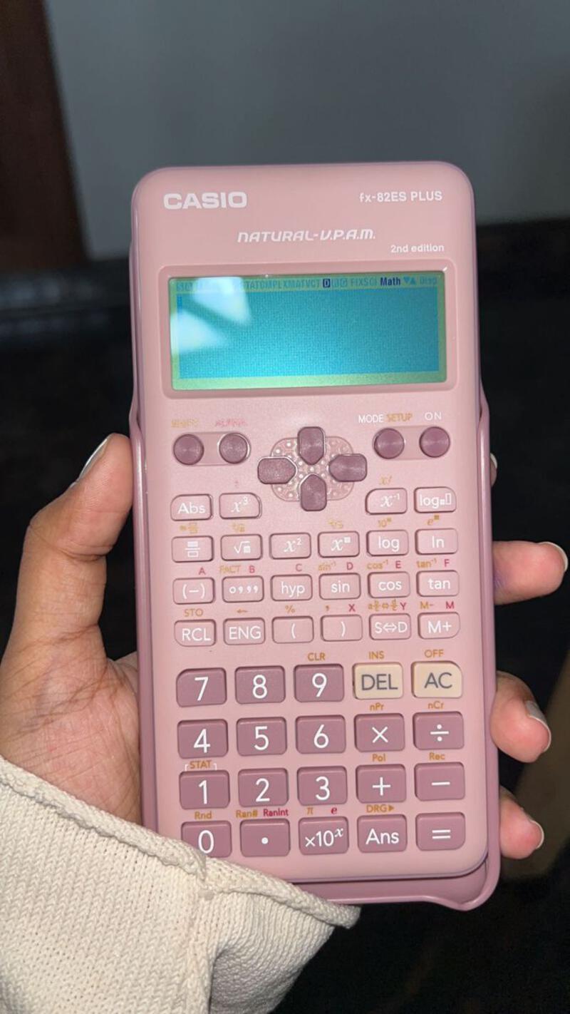 This may contain: a person holding a pink calculator in their left hand with the screen showing