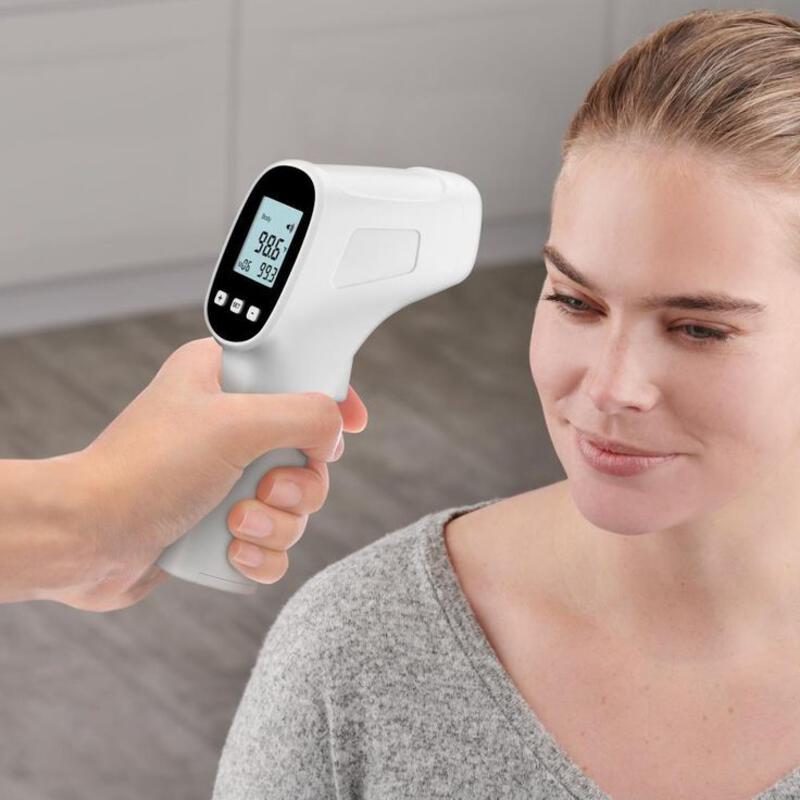 This may contain: a woman is using an infrared thermometer to check her temperature