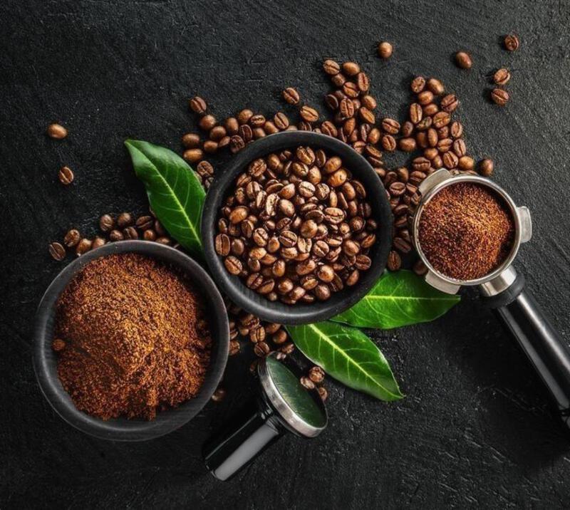 This may contain: coffee beans and ground coffee on a black background with two scoops filled with them