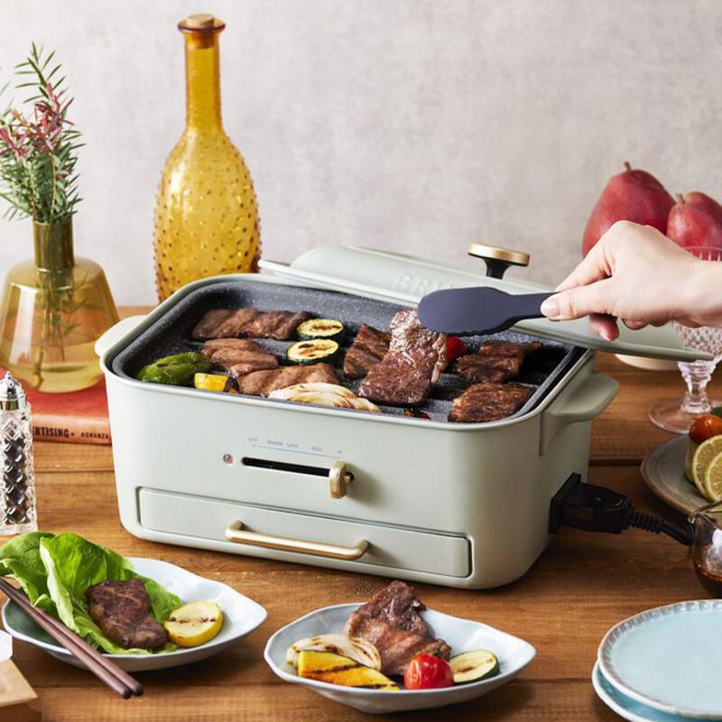 This may contain: a person holding a spatula over a grill on top of a wooden table next to plates and bowls