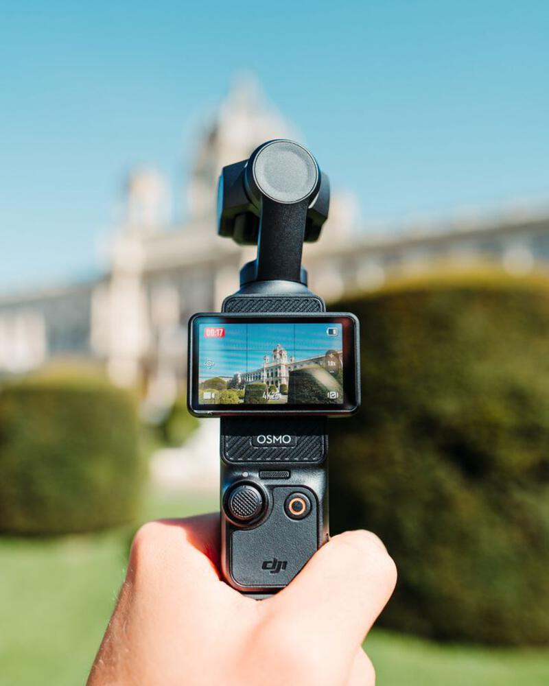This may contain: a person holding up a cell phone to take a photo in front of a building