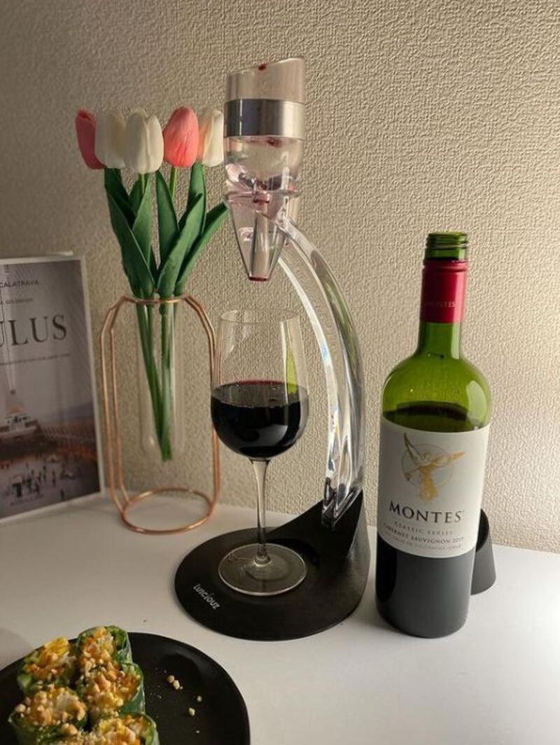 This may contain: a bottle of wine and some food are on a table with a glass of wine