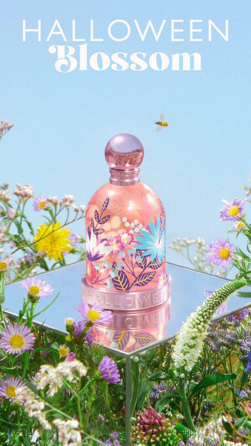 This may contain: a pink bottle sitting on top of a lush green field filled with wildflowers