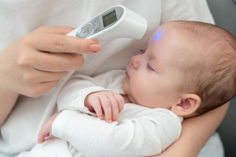 This may contain: a woman is holding a baby with an electronic thermometer in her hand and it