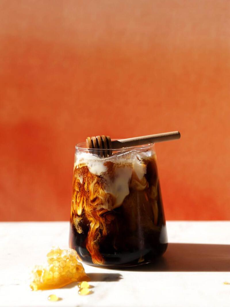 This may contain: a glass jar filled with liquid and a wooden spoon sitting next to it on top of a table
