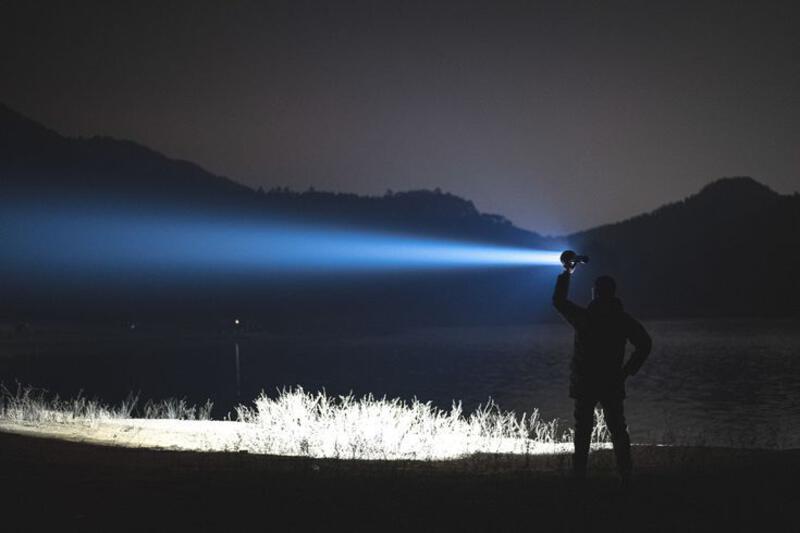 This may contain: a man standing next to a body of water with a light shining on it